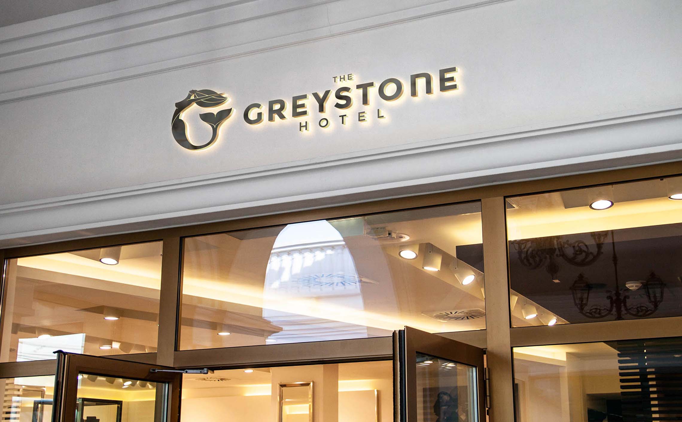 Illuminated metal wall sign with the Greystone logo above the door of the inner patio